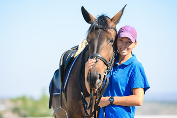 Image showing Portrait of a happy beautiful girl in casual clothes hugging a horse