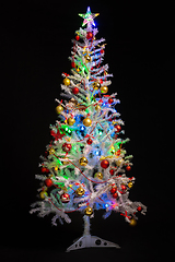 Image showing Festively decorated artificial white Christmas tree on a black background