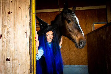 Image showing A girl dressed as a witch holds a horse in a paddock