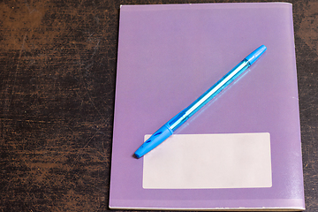 Image showing On the old table lies a closed notebook on which lies a pen