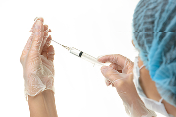 Image showing A medical professional draws a medicine from an ampoule with a syringe