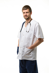 Image showing Portrait of a male doctor, hands stuck in pockets, a phonendoscope hangs around his neck, isolated on white background