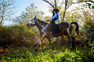 Image showing Girl dressed as a witch riding a horse in halloween celebration