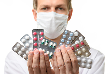 Image showing A man in a medical mask holds a fan of medicines in front of him, focusing on medicines