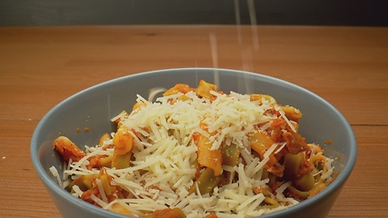 Image showing Cheese topping beiing applied to bowl of pasta in camera motion