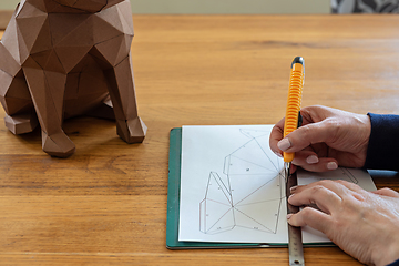 Image showing Somebody is making a cube sculpture with paper, linear and knife