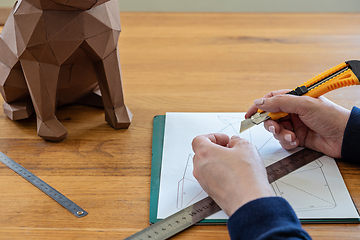 Image showing Somebody is making a cube sculpture with paper, linear and knife