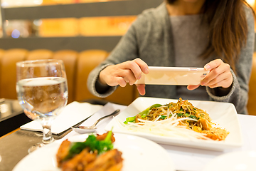 Image showing Woman taking photo on dishes in restaurant