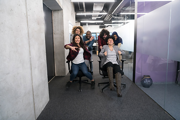 Image showing multiethnics business team racing on office chairs