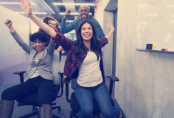 Image showing multiethnics business team racing on office chairs