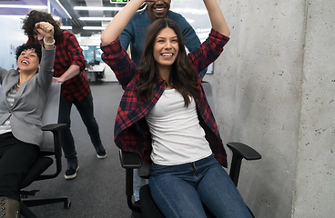 Image showing multiethnics business team racing on office chairs