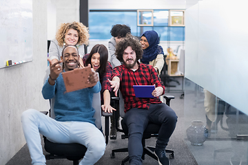 Image showing multiethnics business team racing on office chairs