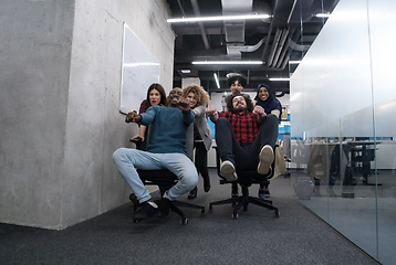 Image showing multiethnics business team racing on office chairs