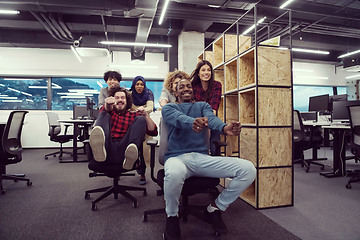 Image showing multiethnics business team racing on office chairs