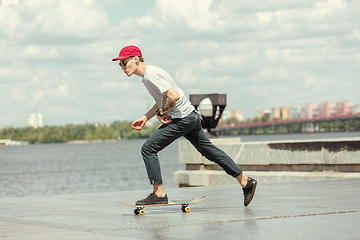 Image showing Skateboarder doing a trick at the city\'s street in sunny day