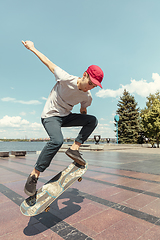 Image showing Skateboarder doing a trick at the city\'s street in sunny day