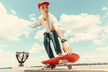 Image showing Skateboarder doing a trick at the city\'s street in sunny day