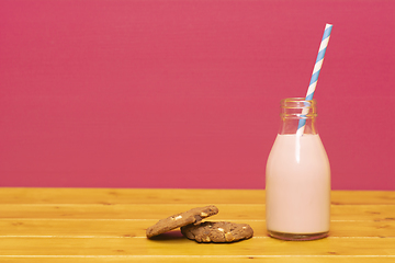 Image showing Strawberry milkshake and straw in a bottle with a cookie