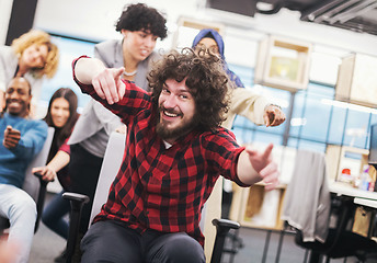 Image showing multiethnics business team racing on office chairs