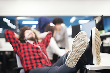 Image showing software developer resting with legs on desk