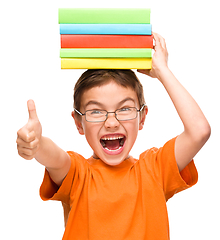 Image showing Little boy is holding a pile of books