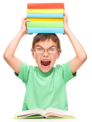 Image showing Little boy is holding a pile of books
