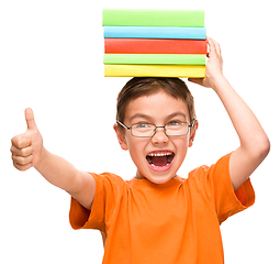 Image showing Little boy is holding a pile of books