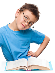 Image showing Young boy is daydreaming while reading book