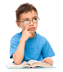 Image showing Young boy is daydreaming while reading book