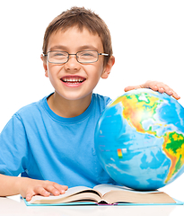 Image showing Little boy is examining globe