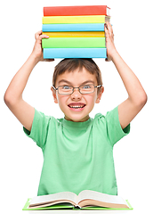 Image showing Little boy is holding a pile of books