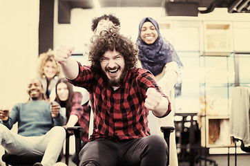 Image showing multiethnics business team racing on office chairs