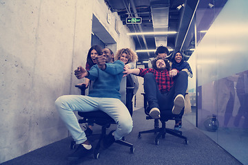 Image showing multiethnics business team racing on office chairs