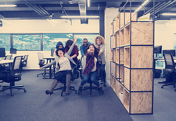 Image showing multiethnics business team racing on office chairs