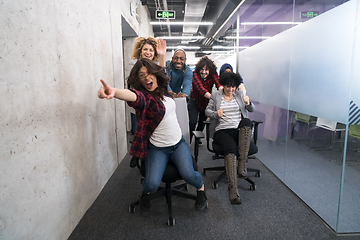 Image showing multiethnics business team racing on office chairs