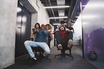 Image showing multiethnics business team racing on office chairs