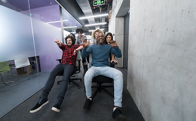 Image showing multiethnics business team racing on office chairs