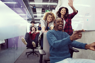 Image showing multiethnics business team racing on office chairs