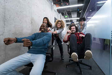 Image showing multiethnics business team racing on office chairs