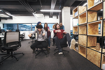 Image showing multiethnics business team racing on office chairs