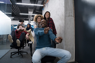 Image showing multiethnics business team racing on office chairs