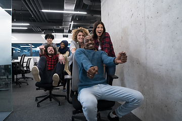 Image showing multiethnics business team racing on office chairs