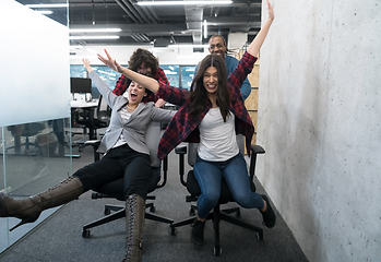 Image showing multiethnics business team racing on office chairs