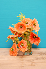 Image showing Vase of pale pink poppies on a wooden table