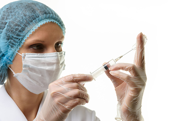 Image showing A nurse wearing a mask and gloves draws medicine with a syringe from an ampoule, isolated on a white background