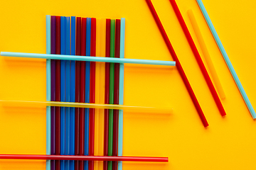 Image showing Multi-colored cocktail tubes lie on a yellow background