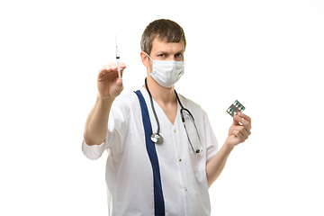 Image showing Male doctor holding a syringe with medicine in one hand and pills in the other hand, isolated on white background