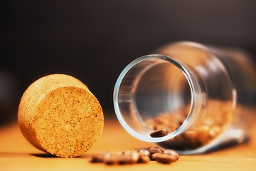 Image showing Roasted coffee beans on table with jar