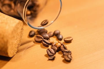 Image showing Roasted coffee beans on table with jar