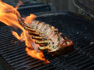 Image showing Large grilled rack of lamb over an open flame